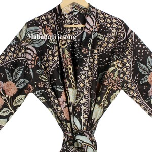 Puede incluir: Batista de kimono de estampado floral negro con cierre de nudo. La bata tiene un patrón paisley con acentos rosa, verde y blanco.