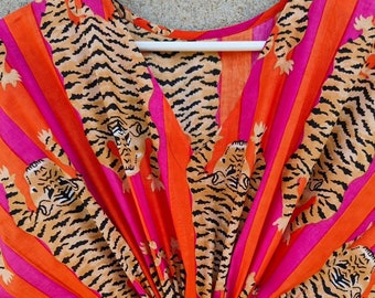 May include: A pink and orange striped fabric with a tiger print. The fabric has a V-neck and is gathered at the bottom.