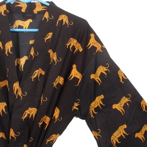 May include: Black kimono robe with a gold leopard print pattern. The robe has long sleeves and a tie closure at the waist.