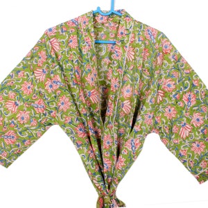 Könnte beinhalten: Eine grüne Baumwollrobe mit einem Blumendruck in Rosa- und Blautönen. Die Robe hat einen Schalkragen und lange Ärmel.