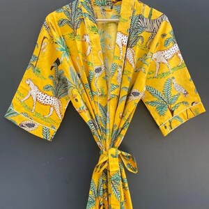May include: A yellow cotton robe with a jungle print featuring leopards, zebras, and palm trees.