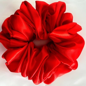 Puede incluir: Un scrunchie de satén rojo brillante, un accesorio para el cabello para atar el cabello largo.