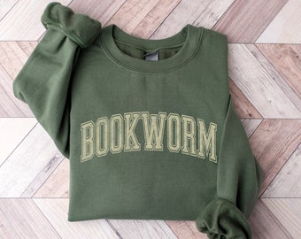 Pode incluir: Uma camisa de moletom verde com o texto "BOOKWORM" em cor amarelo-dourado na frente.