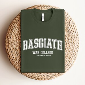 Op de afbeelding: Een groen T-shirt met witte tekst die "Basgiath War College Lightning Wielder" luidt.