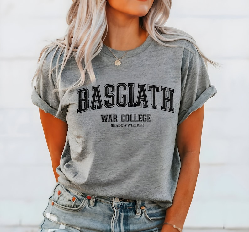 Op de afbeelding: Grijs T-shirt met zwarte tekst die "BASGIATH WAR COLLEGE SHADOW WIELDER" luidt