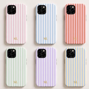 Pode incluir: Seis capas para smartphone dispostas em duas filas, cada uma com riscas verticais em rosa pastel, azul, coral, verde menta, lavanda ou amarelo e azul. Cada capa tem um recorte preto para a câmara e as iniciais SL douradas na parte inferior.