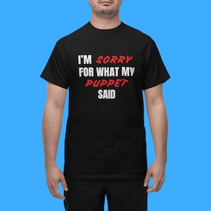 May include: Black t-shirt with white text that reads "I'm Sorry For What My Puppet Said". The words "Sorry" and "Puppet" are in red.