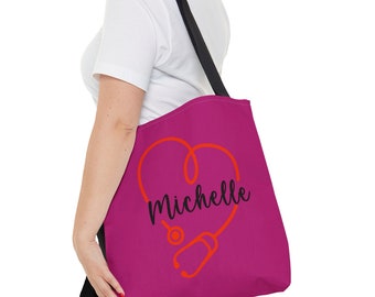 May include: A pink tote bag with a black strap and a red stethoscope design in the shape of a heart. The name "Michelle" is written in black cursive inside the heart.