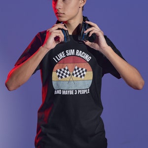 May include: A black t-shirt with a retro-style graphic that says "I like sim racing and maybe 3 people". The graphic features a sunset with two checkered flags.
