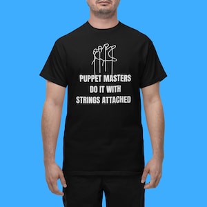 May include: Black t-shirt with a white graphic of a hand holding strings attached to five figures. The text "Puppet Masters Do It With Strings Attached" is printed below the graphic.