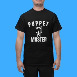 May include: Black t-shirt with white text that reads "Puppet Master" and a graphic of a puppet with strings.