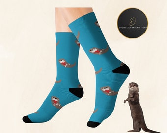 May include: A pair of blue socks with a pattern of brown otters holding red hearts. The socks are on a white background. The text "Digital Chan Creations" is visible in the upper right corner of the image.