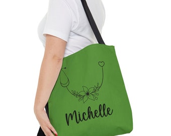 May include: Green tote bag with a black stethoscope, flower, and heart design. The name "Michelle" is printed in black cursive lettering.