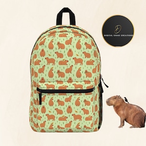 May include: A green backpack with a repeating pattern of capybaras and yellow flowers. The backpack has a black zipper and a black strap. The text "DIGITAL CHAN CREATIONS" is visible on a black circle.