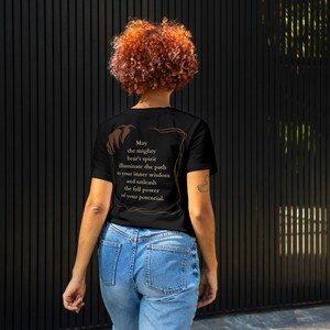 May include: A black t-shirt with a brown text design that reads "May the mighty bear's spirit illuminate the path to your inner wisdom and unleash the full power of your potential."