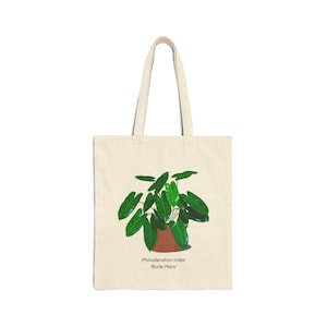 Peut inclure: Un sac fourre-tout beige avec une illustration d'une plante verte Philodendron imbe 'Burle Marx' dans un pot brun.