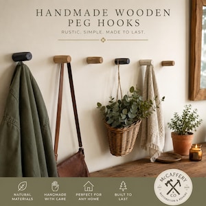May include: Six cylindrical wooden peg hooks mounted on a wall, displaying varying wood tones from light to dark. The hooks hold a green jacket, a brown leather bag, a woven basket with greenery, and a beige towel. Text reads HANDMADE WOODEN PEG HOOKS.
