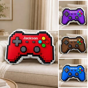 May include: Pixelated video game controller-shaped pillows in red, purple, brown, and blue. Each pillow has a white border and the name "Jackson" printed on it. The pillows feature colorful buttons and a directional pad.