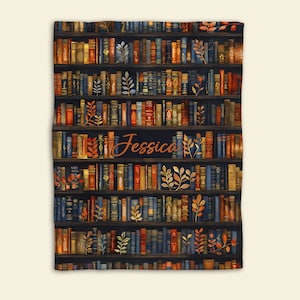 May include: A personalized throw blanket with a dark blue background featuring a bookshelf filled with colorful books and gold leaf accents. The name "Jessica" is written in orange script on the blanket.