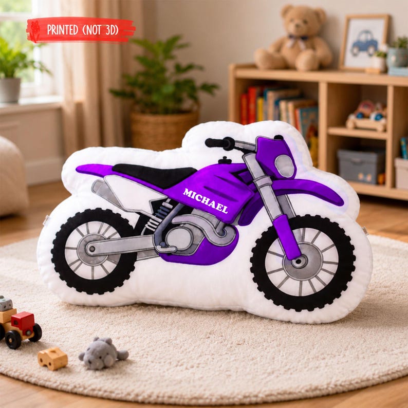 Puede incluir: Un coj&iacute;n con forma de motocicleta en blanco, morado, negro y plateado. El coj&iacute;n tiene el nombre "MICHAEL" en el lateral. El texto "PRINTED (NOT 3D)" est&aacute; impreso en una pancarta roja. El coj&iacute;n est&aacute; sobre una alfombra clara.