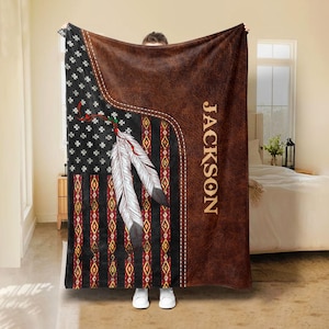 May include: A brown fleece blanket with a personalized name "JACKSON" printed on the right side. The left side features a red, white, and blue American flag with a Native American feather design.