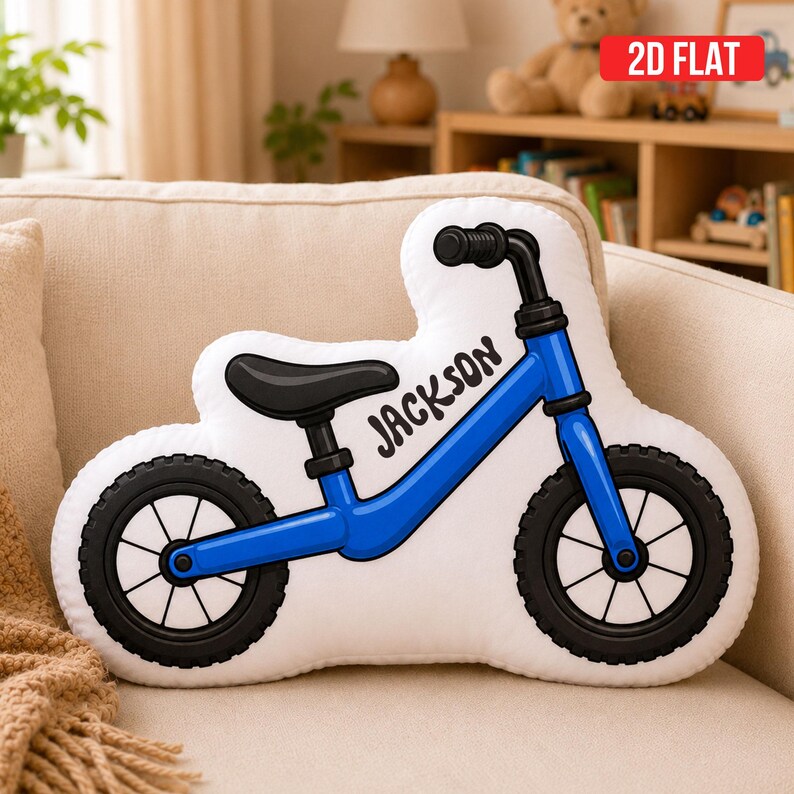 May include: A white throw pillow shaped like a balance bike with a blue frame, black seat, and black tires. The name Jackson is printed in black script on the frame. The pillow features a 2D flat design with clear black outlines.