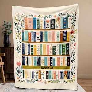 Può includere: Una coperta bianca con un'illustrazione colorata di una libreria piena di libri. La libreria è decorata con fiori e piante verdi. Il testo "JESSICA" è stampato sullo scaffale.