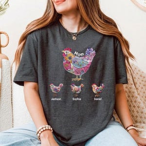 May include: Dark grey t-shirt with a colourful patchwork chicken design and the word "Mom" above it. Below the chicken are three smaller chickens with the names "Jackson", "Sophia", and "Daniel".