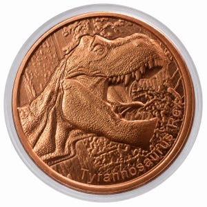 May include: A round copper-colored coin featuring a detailed relief of a Tyrannosaurus Rex head with its mouth open. The dinosaur is depicted in profile against a textured background. The text Tyrannosaurus Rex is embossed along the bottom edge.