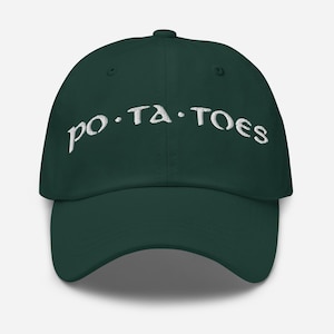 Può includere: Un cappellino da baseball verde scuro con la scritta "po.ta.toes" ricamata in bianco sul davanti. Il cappellino ha una visiera curva e una chiusura con cinturino in tessuto sul retro.