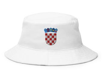 May include: White bucket hat featuring an embroidered Croatian coat of arms. The coat of arms is a shield with a red and white checkered pattern, topped with a crown. The hat is a casual accessory.