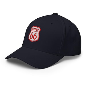 May include: Navy blue baseball cap with a red and white embroidered patch that reads "ORDER 66" in a shield shape. The cap has a curved brim and a structured fit.