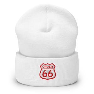May include: White beanie with a red embroidered design. The design is a red shield with the text "ORDER" above the number "66". The beanie is made of a soft, knitted material.
