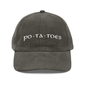 Puede incluir: Gorra de béisbol de pana verde oliva con la palabra "po.ta.toes" bordada en blanco. La gorra tiene una visera curva y una parte superior redondeada.