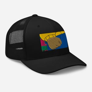 May include: Black trucker hat with a mesh back and a curved brim. The front panel features an embroidered design of a cartoon character's arm and fist in yellow, blue, and brown.