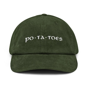 Op de afbeelding: Donkergroene corduroy baseballcap met het woord "po·ta·toes" in wit geborduurd. De pet heeft een gebogen klep en een verstelbare band. Een leuke accessoire voor casual wear.