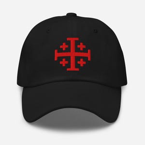 Könnte beinhalten: Schwarze Baseballkappe mit einem roten Jerusalemer Kreuz auf der Vorderseite. Die Kappe hat einen gebogenen Schirm und einen verstellbaren Riemen. Das Jerusalemer Kreuz ist ein christliches Symbol.