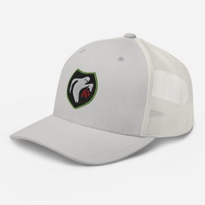 May include: A light gray baseball cap with a white mesh back. The cap features a black, green, and red embroidered patch with a ghost-like figure. The cap has a curved brim and a button on top.