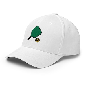 May include: White baseball cap with an embroidered green pickleball paddle and yellow pickleball. The cap has a curved brim and a structured fit, perfect for outdoor activities or casual wear. A stylish accessory for pickleball enthusiasts.