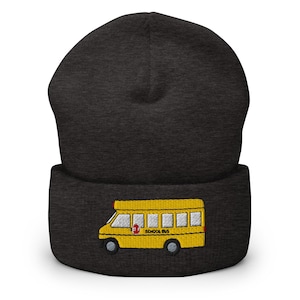 Puede incluir: Gorro gris oscuro con un diseño de autobús escolar amarillo bordado. El autobús escolar tiene ruedas negras, una señal de stop roja y las palabras "SCHOOL BUS" en negro. Un accesorio cálido y cómodo.
