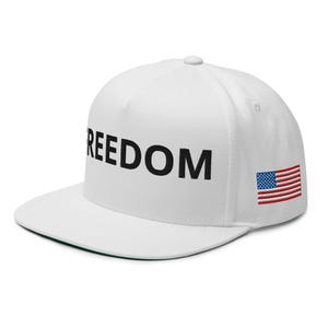 Könnte beinhalten: Weiße Baseballkappe mit dem Wort "FREEDOM" in schwarzer Schrift. Auf der Seite ist die amerikanische Flagge aufgestickt. Die Kappe hat einen flachen Schirm und einen Knopf oben.