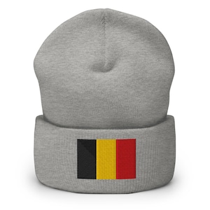 Pode incluir: Um gorro cinzento com a bandeira belga bordada na frente. A bandeira apresenta listras verticais pretas, amarelas e vermelhas. O gorro é um estilo simples e casual.