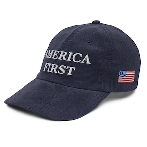 May include: Navy blue corduroy baseball cap with the words "AMERICA FIRST" embroidered in white on the front. The cap features a small embroidered American flag on the side.
