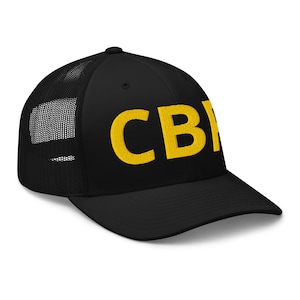 May include: Black trucker hat with a mesh back and a curved brim. The hat features the embroidered letters "CB" in a bold, yellow font across the front. The hat is a classic baseball cap style.