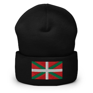Peut inclure: Bonnet noir avec bord replié. Le bonnet présente un drapeau brodé aux couleurs rouge, blanc et vert. Le motif du drapeau comprend une croix blanche et des lignes diagonales vertes.