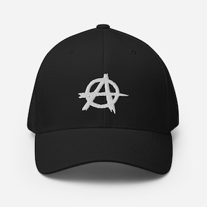 May include: Black baseball cap with a white embroidered anarchy symbol on the front. The cap has a curved brim and a structured fit. The hat is made of a durable material and is suitable for everyday wear.