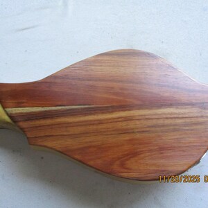 May include: A wooden mandolin body with a natural finish. The instrument's back is a rich, reddish-brown with visible wood grain. The neck is a lighter, yellowish colour. The date and time stamp is visible on the bottom right.