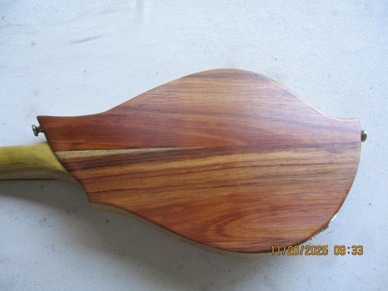 May include: A wooden mandolin body with a natural finish. The instrument's back is a rich, reddish-brown with visible wood grain. The neck is a lighter, yellowish colour. The date and time stamp is visible on the bottom right.