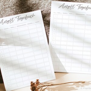 K&ouml;nnte beinhalten: Zwei druckbare Seiten mit dem Titel "Angst Tagebuch" auf Deutsch. Die Seiten sind in Spalten mit &Uuml;berschriften f&uuml;r Datum, Situation, Details, emotionale Reaktion, Achtsamkeitstechniken und Beobachtungen unterteilt.