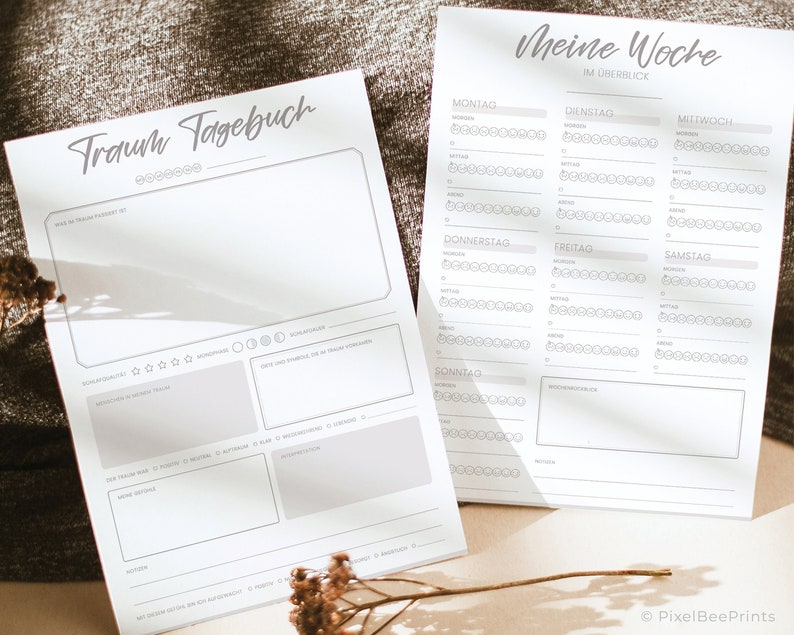 K&ouml;nnte beinhalten: Zwei druckbare Seiten zum Journalisieren von Tr&auml;umen und zur Verfolgung deiner Woche. Die erste Seite tr&auml;gt den Titel "Traumtagebuch" und hat Abschnitte zum Aufzeichnen des Traums, zur Bewertung des Traums und zum Notieren von Symbolen oder Themen. Die zweite Seite tr&auml;gt den Titel "Meine Woche" und hat ein Raster f&uuml;r jeden Tag der Woche mit Kreisen zur Bewertung deiner Stimmung.